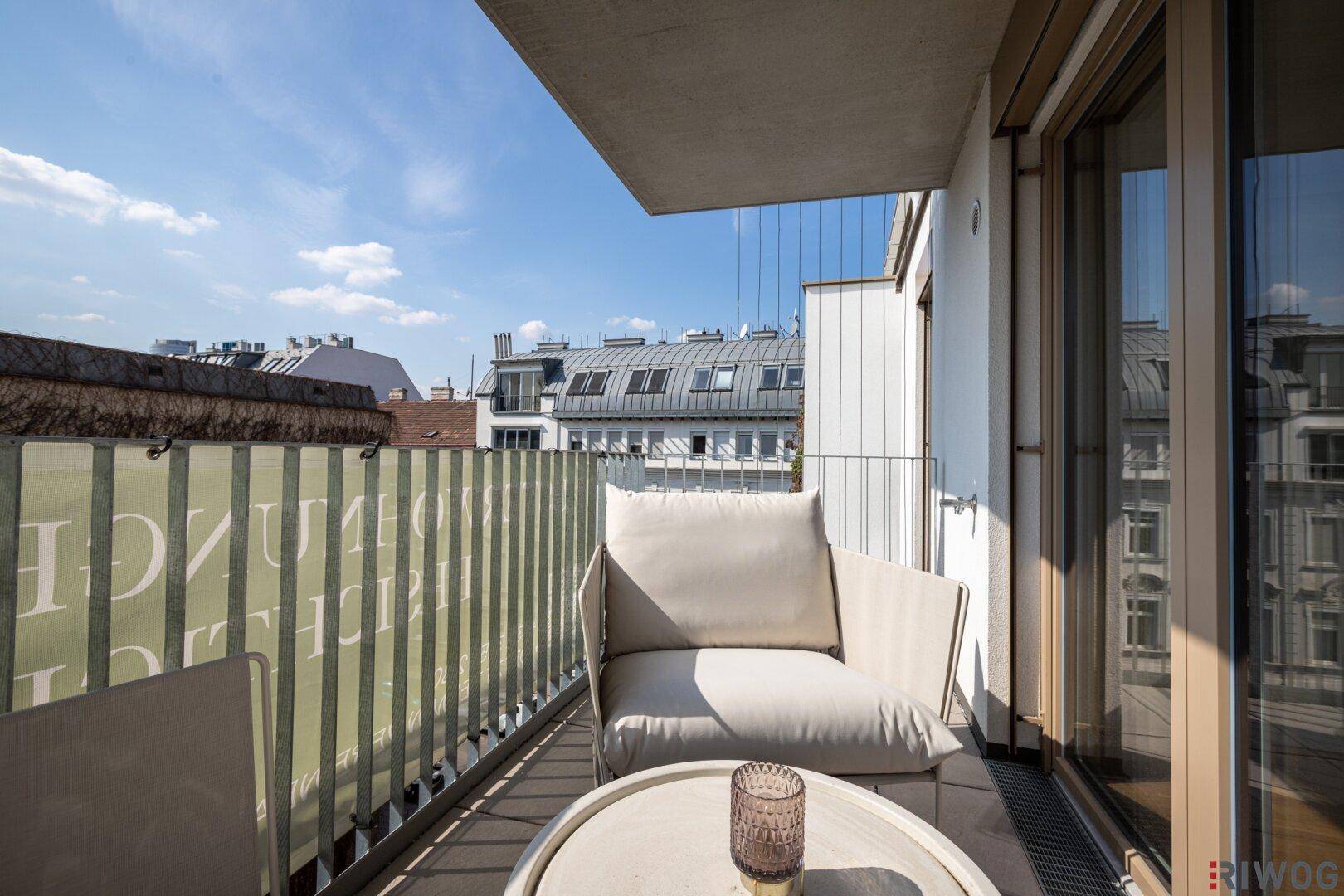 Geräumiger Balkon mit bequemen Stühlen und weitem Blick über die Stadtlandschaft.