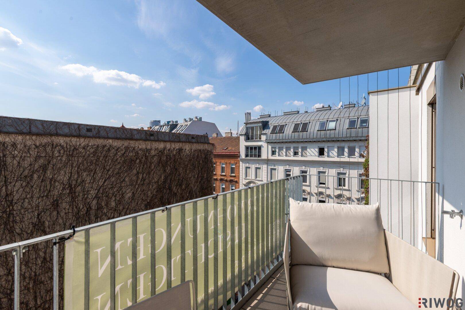 Sonniger Balkon mit Blick auf die Stadt und eine begrünte Wand.