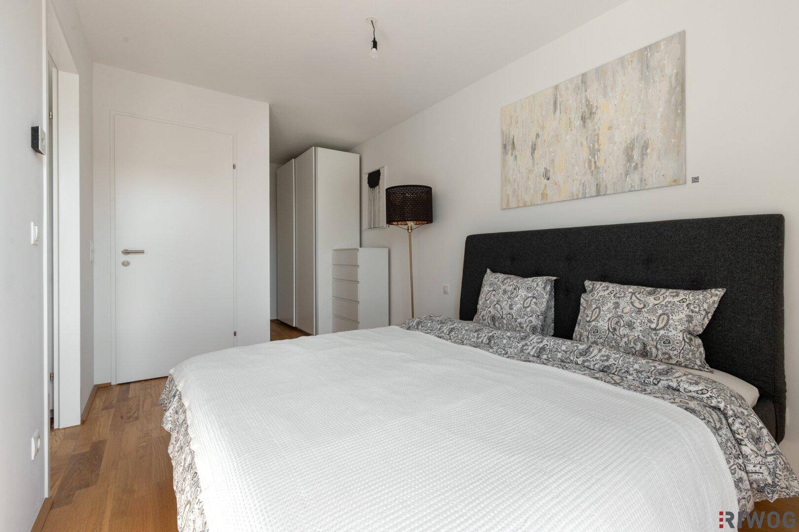 Schlafzimmer mit Holzboden und Blick auf den Kleiderschrankbereich.
