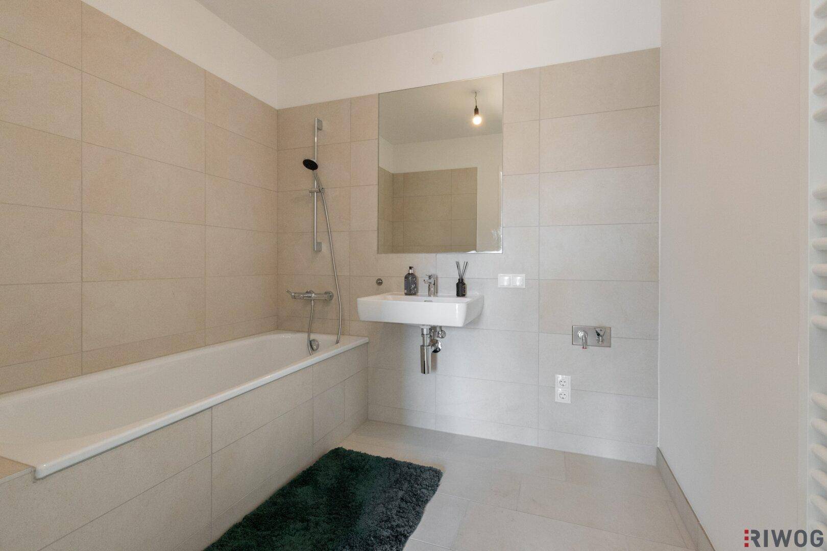 Modernes Badezimmer mit Badewanne, Einzelwaschbecken und hellen Fliesen.