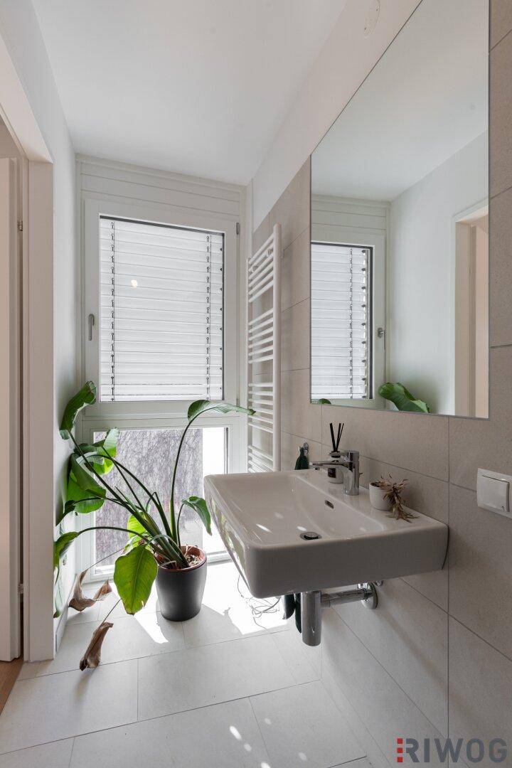 Modernes Badezimmer mit Fenster, Einzelwaschbecken und beheiztem Handtuchhalter.