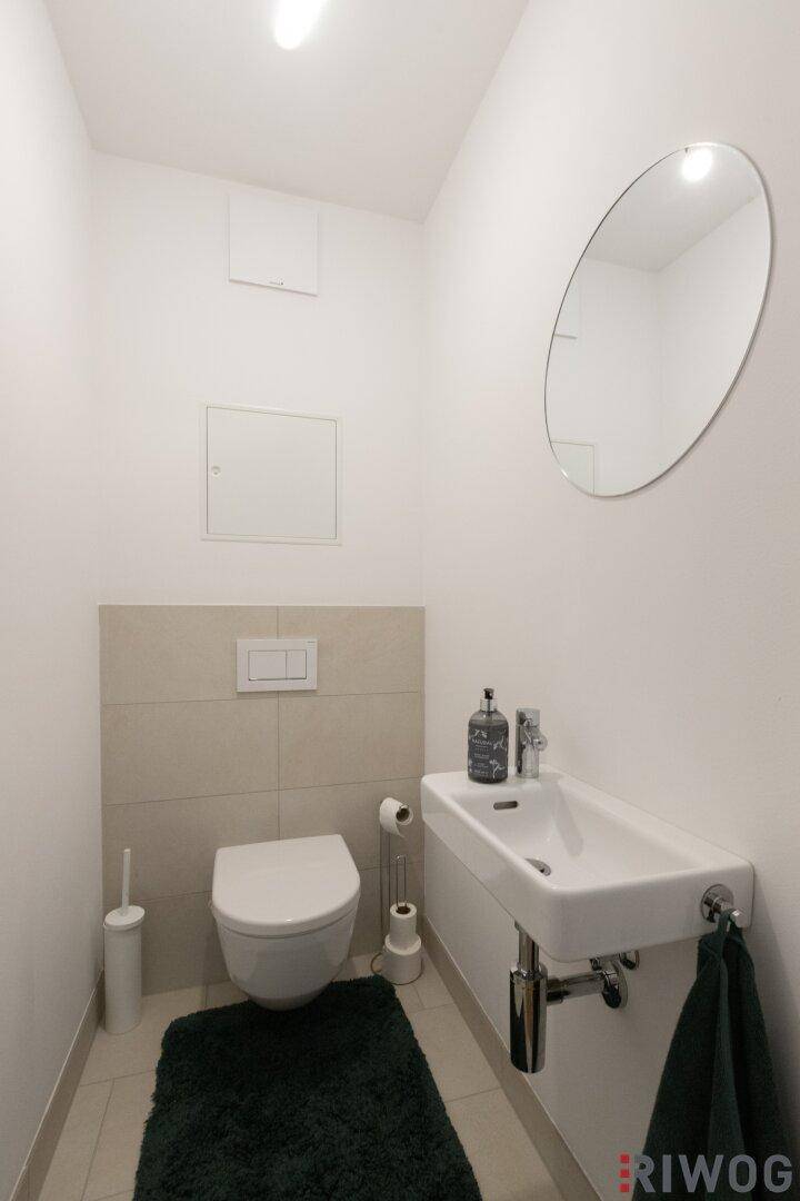 Modernes Gäste-WC mit wandhängender Toilette und kleinem Waschbecken.
