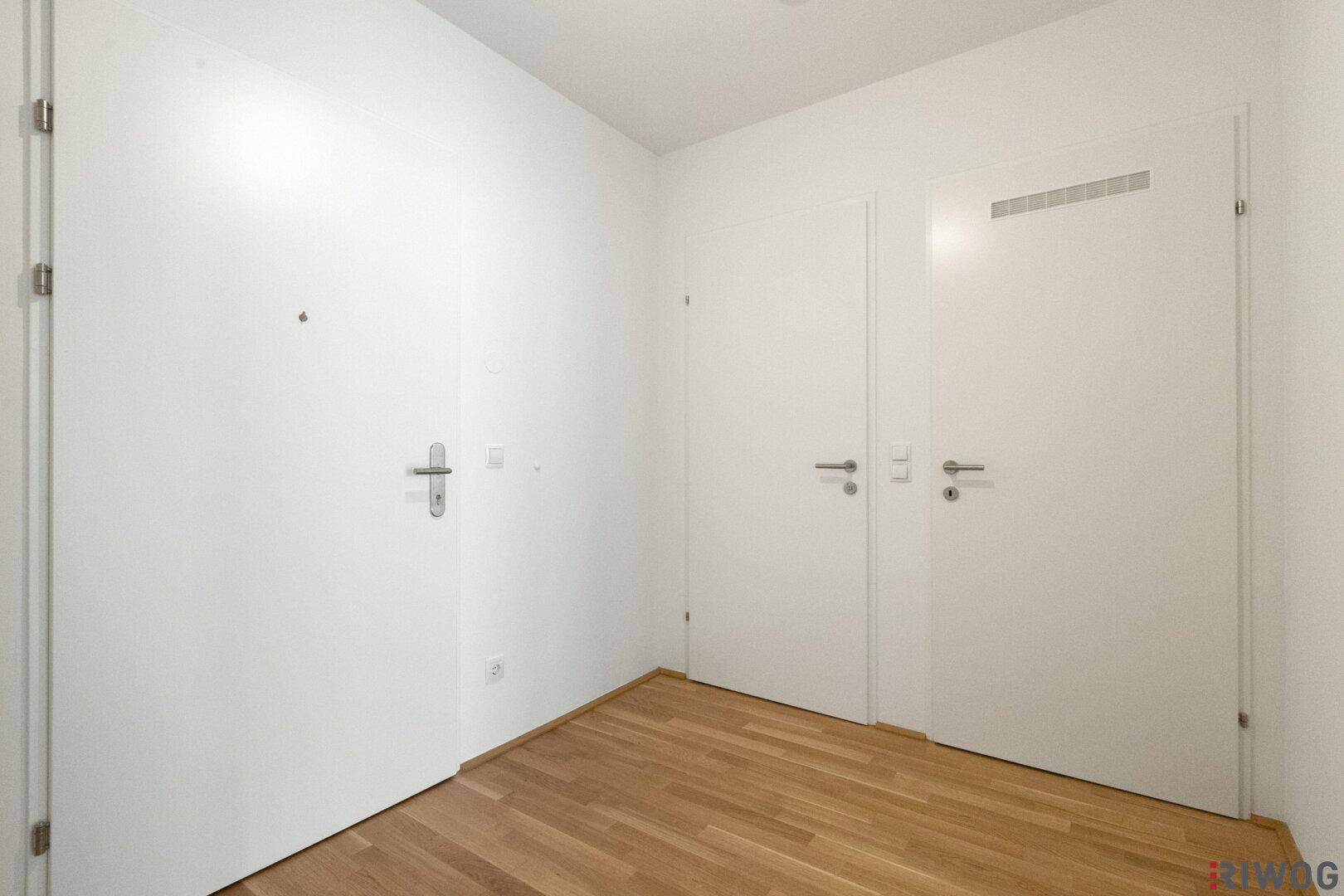 Heller Flur mit mehreren Türen und Parkettboden, der verschiedene Wohnbereiche verbindet.
