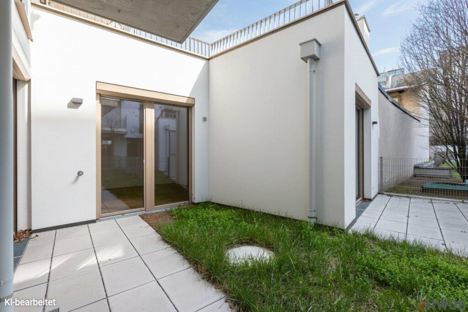 Außenbereich mit gepflasterter Terrasse und kleiner Grünfläche, angrenzend an das Gebäude.