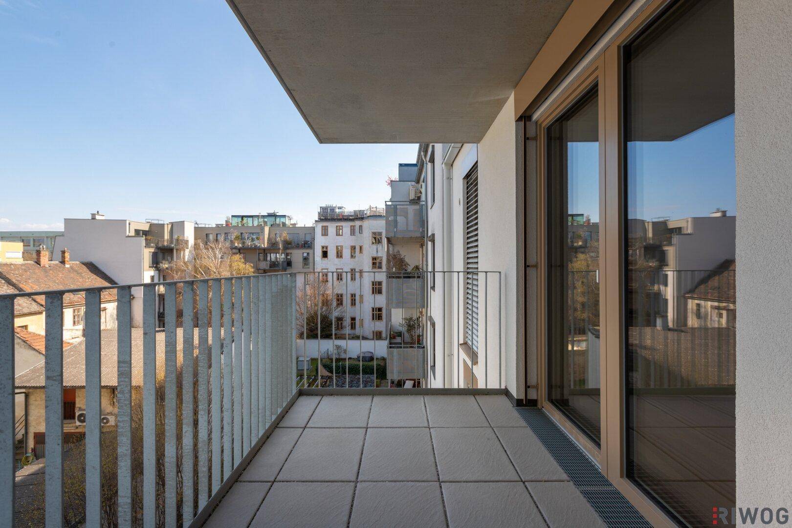 Heller Balkon mit Fliesenboden und Blick auf die umliegenden Gebäude.