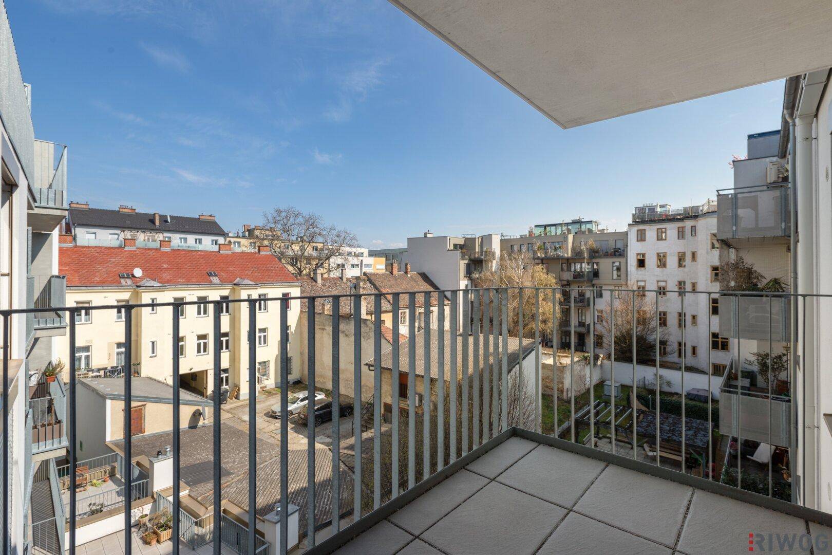 Balkon mit Fliesenboden und weitem Blick über die Dächer der Stadt.