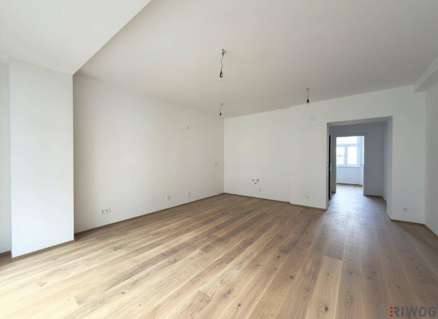 Heller, leerer Raum mit Parkettboden und Zugang zu einem weiteren Zimmer, vielseitig nutzbar.