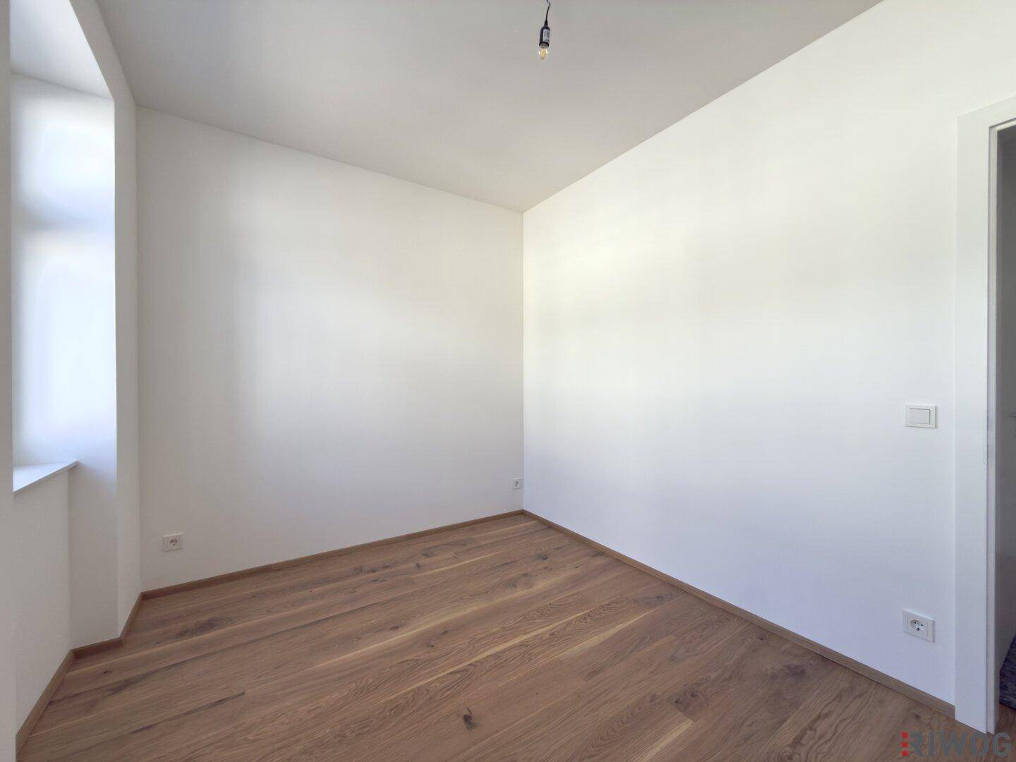 Geräumiges Zimmer mit hellem Parkettboden und weißer Wandgestaltung, bietet vielseitige Nutzungsmöglichkeiten.