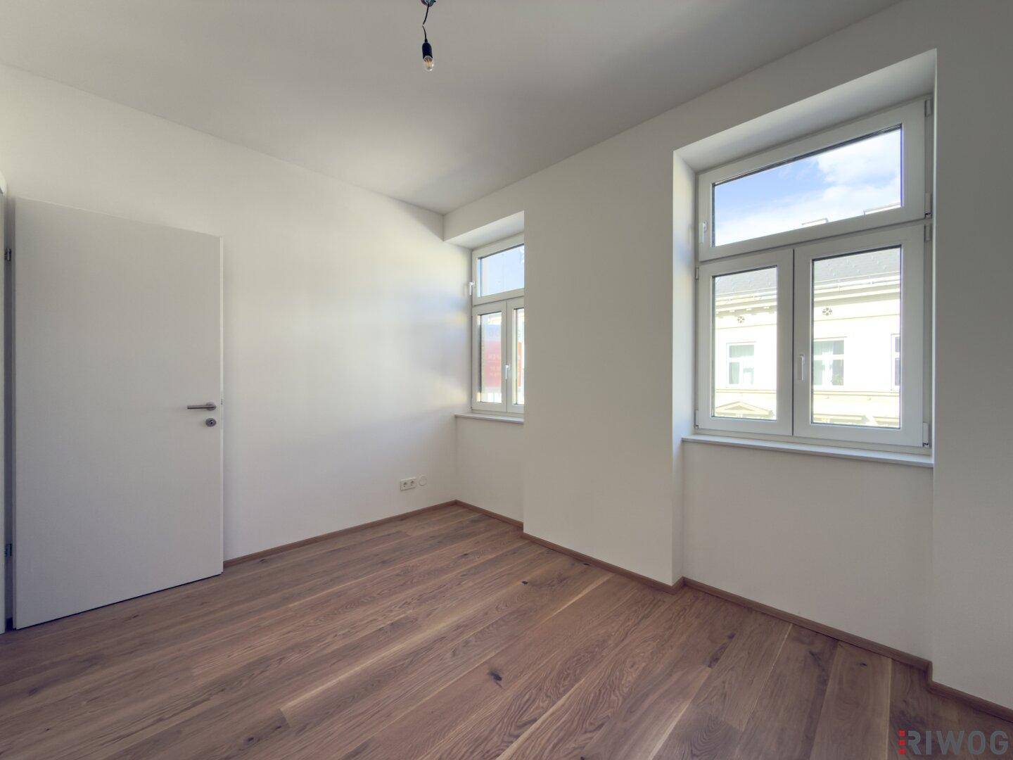 Helles Zimmer mit Parkettboden und Blick nach draußen, bietet eine angenehme Wohnatmosphäre.