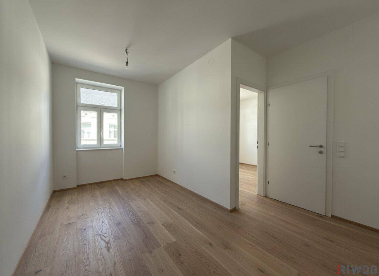 Helles Zimmer mit neuem Parkettboden und weiß gestrichenen Wänden, bereit zum Einzug.