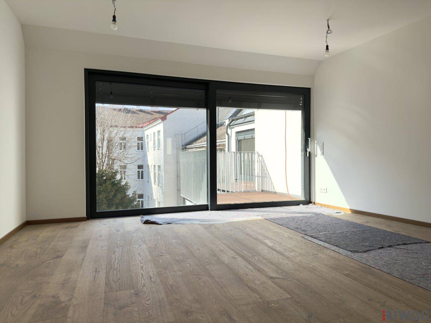 Heller Wohnraum mit großen Schiebetüren zum Balkon und neuem Holzboden.