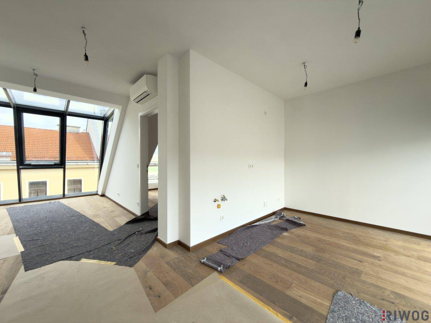 Geräumiger, heller Raum mit Holzboden, Dachschrägen und Klimaanlage, noch im Ausbau.