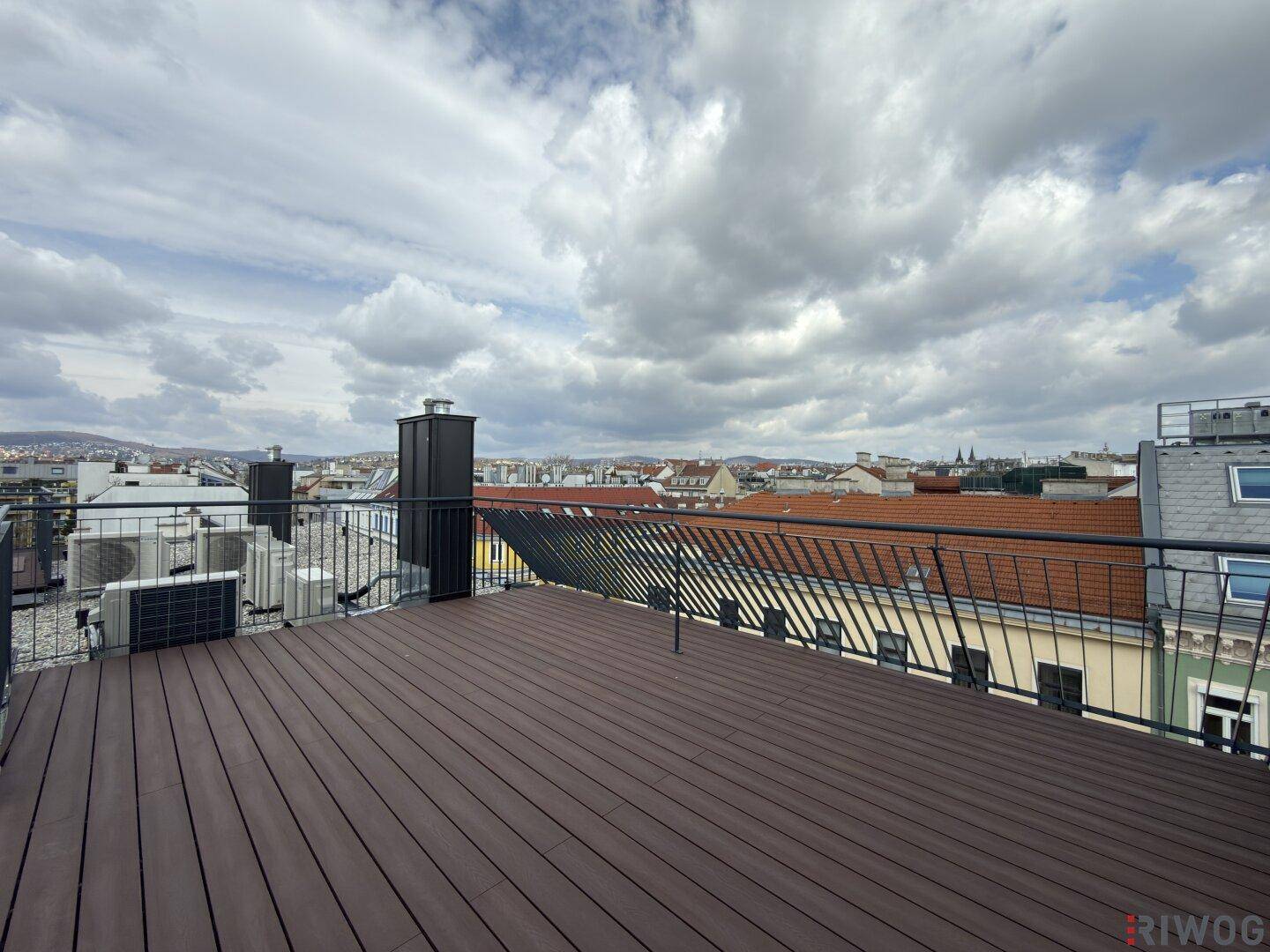 Weitläufige Dachterrasse mit modernem Geländer und Panoramablick über die Dächer der Stadt.