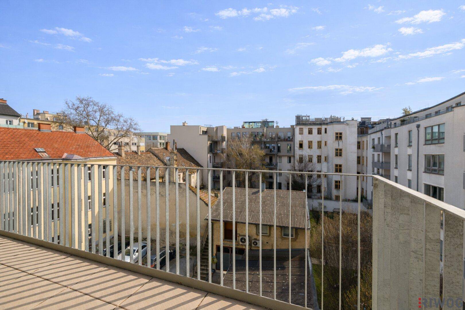 Balkon mit Blick auf die Dächer der Stadt und die umliegenden Gebäude an einem klaren Tag.