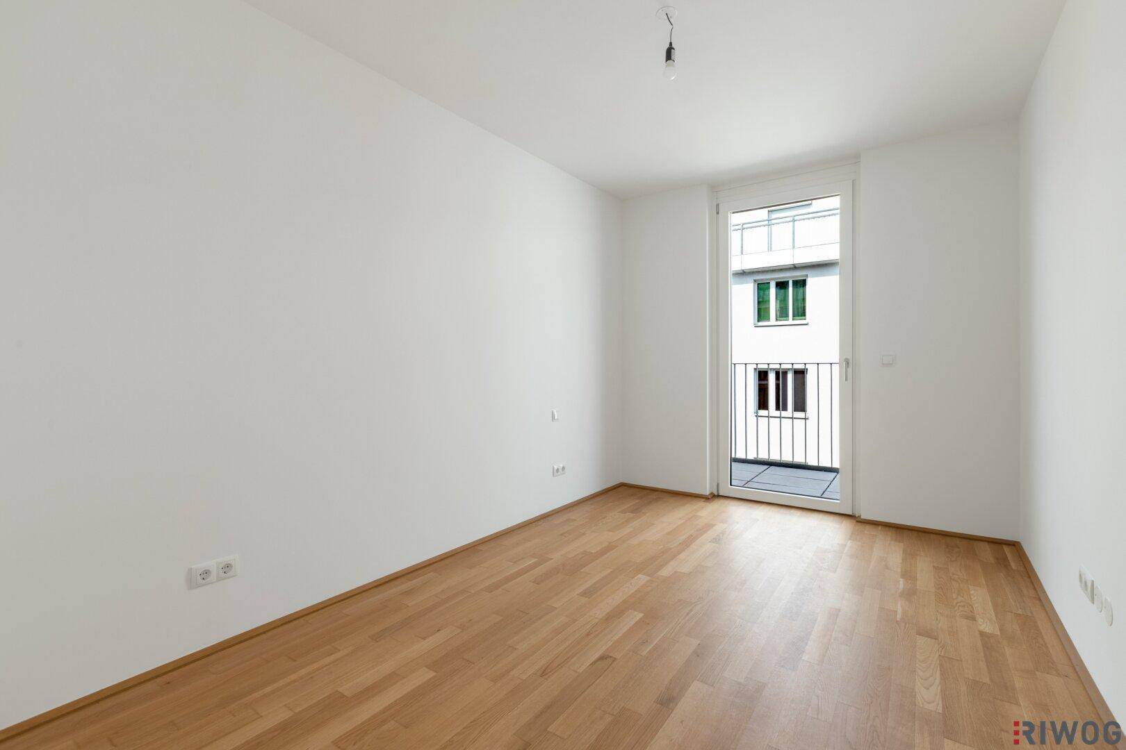 Leeres Zimmer mit Parkettboden und französischem Balkon, ideal für ein Schlafzimmer.