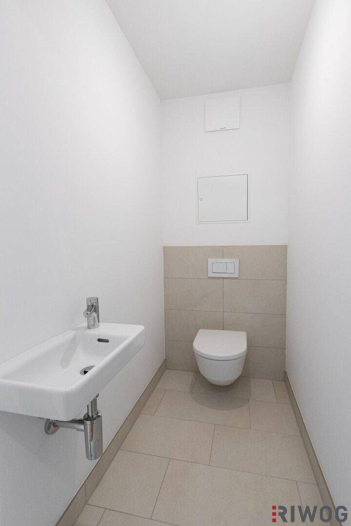 Modernes Gäste-WC mit wandhängender Toilette und kleinem Waschbecken.
