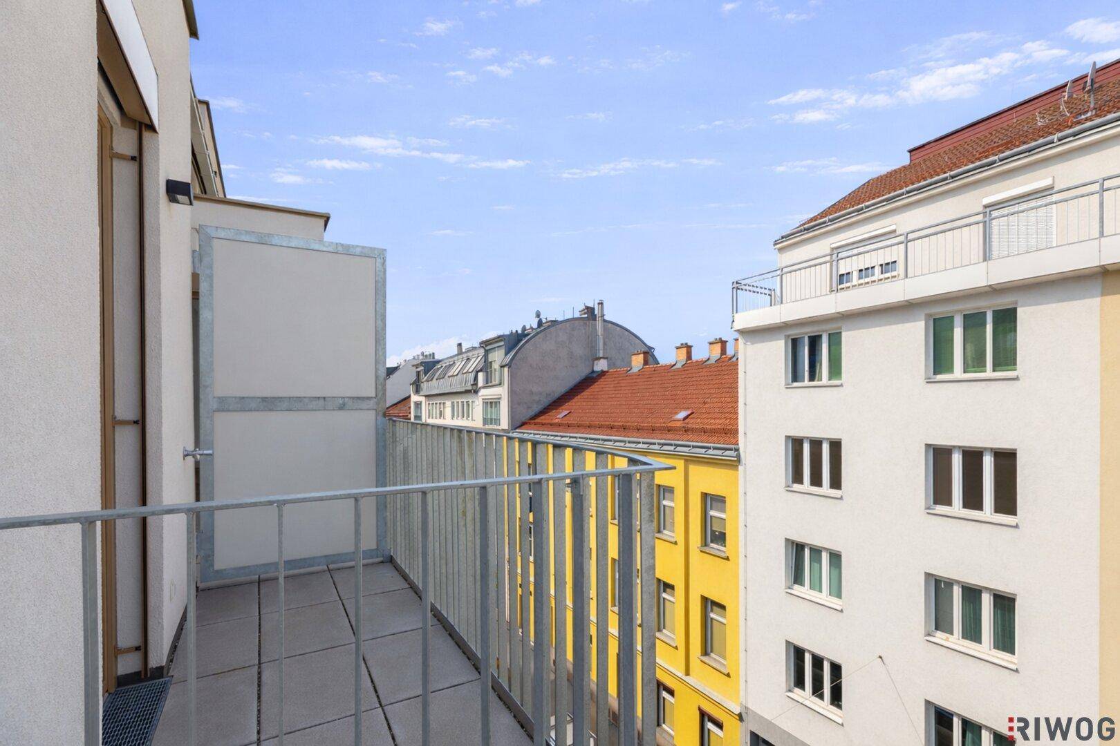 Schmaler Balkon mit Fliesenboden und seitlichem Blick auf die Stadt.