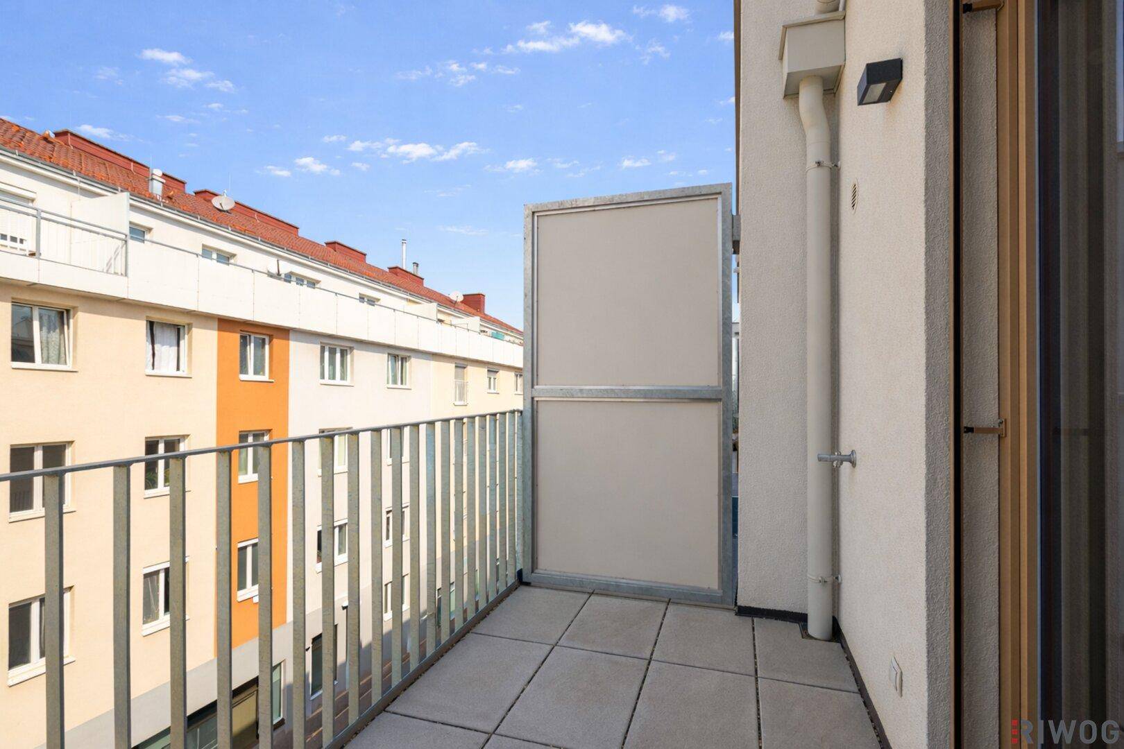 Balkon mit Fliesenboden und Blick auf die gegenüberliegenden Wohngebäude.