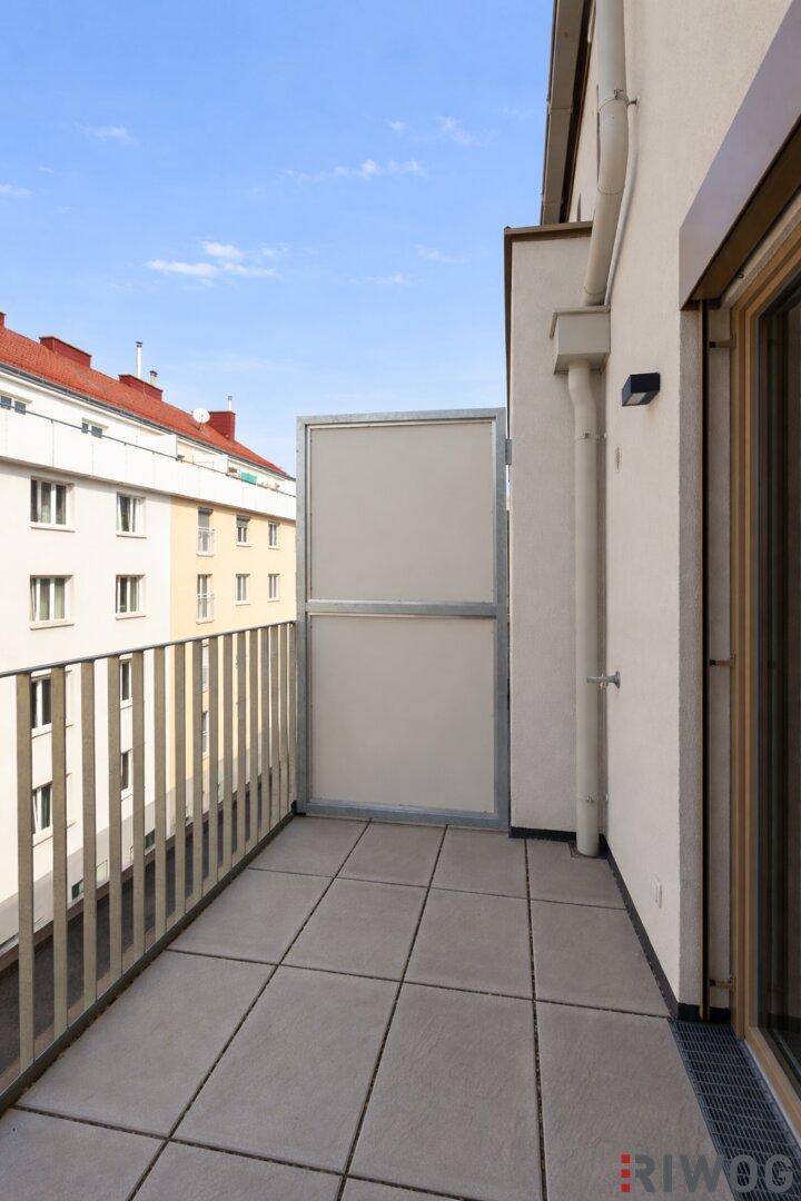 Heller Balkon mit Fliesenboden und Blick auf die umliegenden Gebäude.