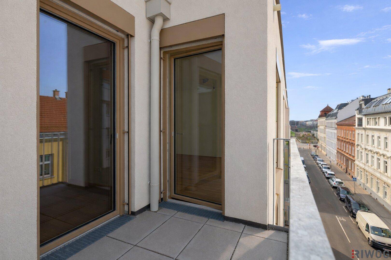 Balkon mit Fliesenboden und weitem Blick über die Straße und Stadt.