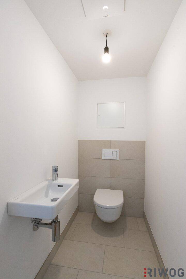 Gäste-WC mit wandhängender Toilette und modernem Waschbecken.