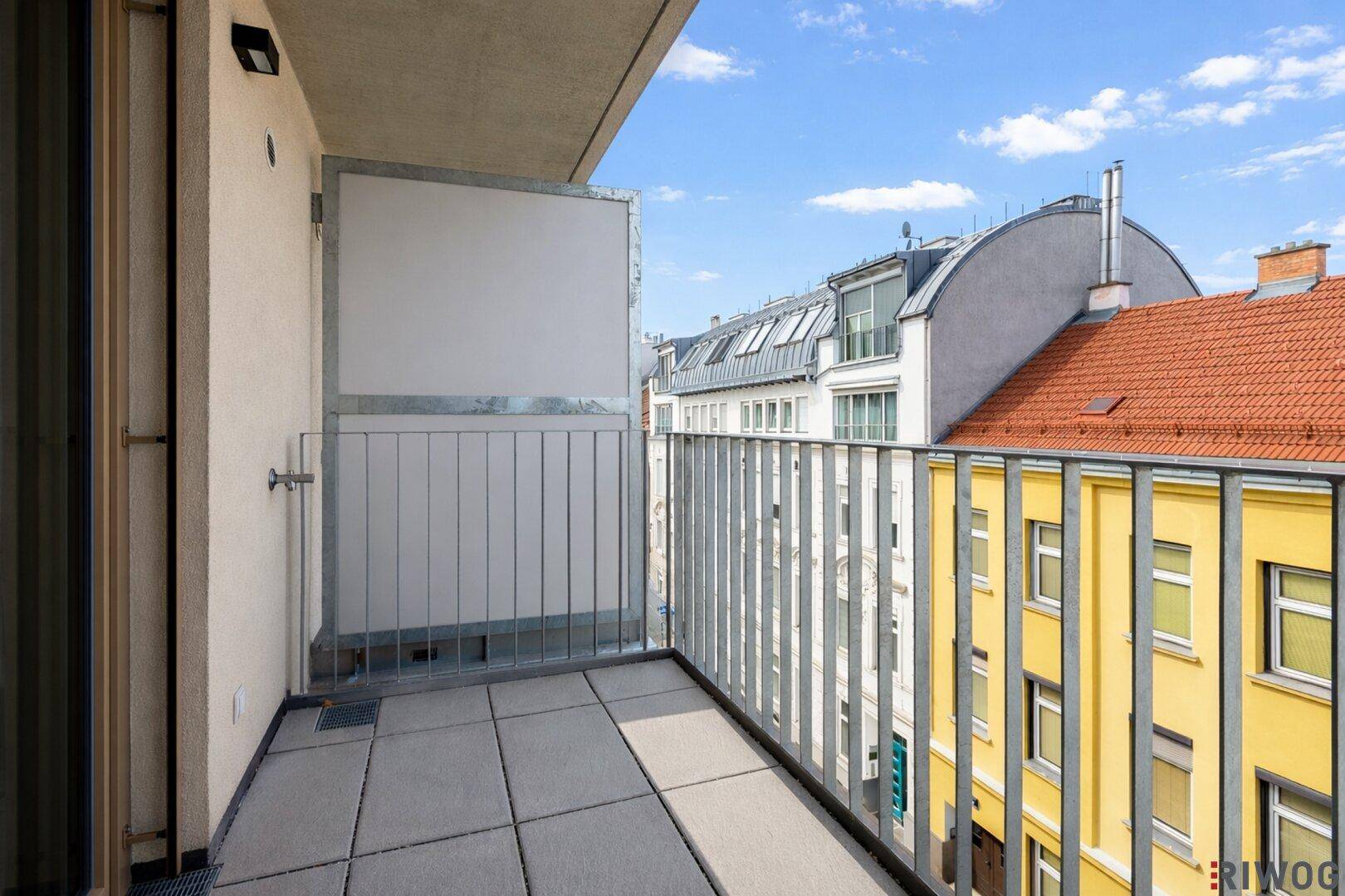 Leerer Balkon mit Fliesenboden und Blick auf die umliegende Stadtbebauung.