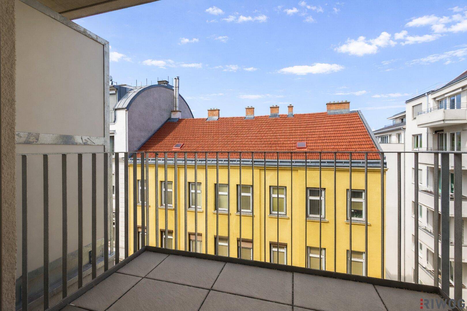 Geräumiger Balkon mit Fliesenboden und weitem Blick über die Dächer der Stadt.