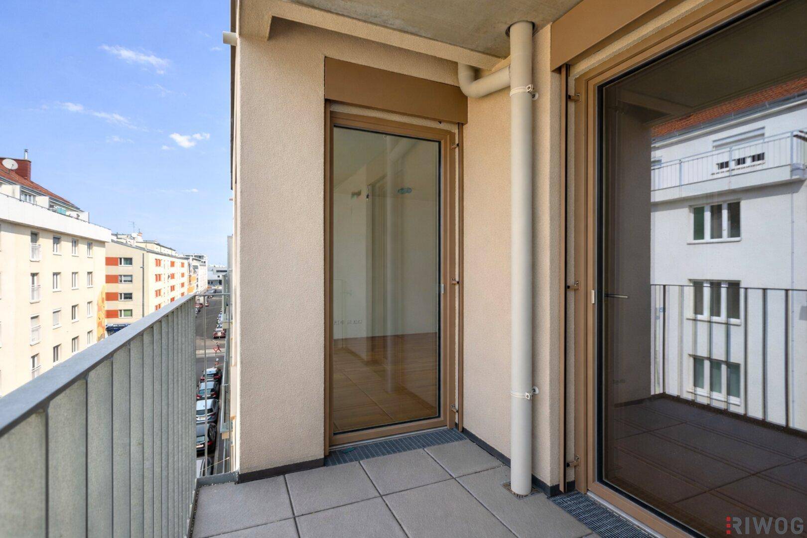 Schmaler Balkon mit Fliesenboden und Blick auf die Straße und angrenzende Gebäude.