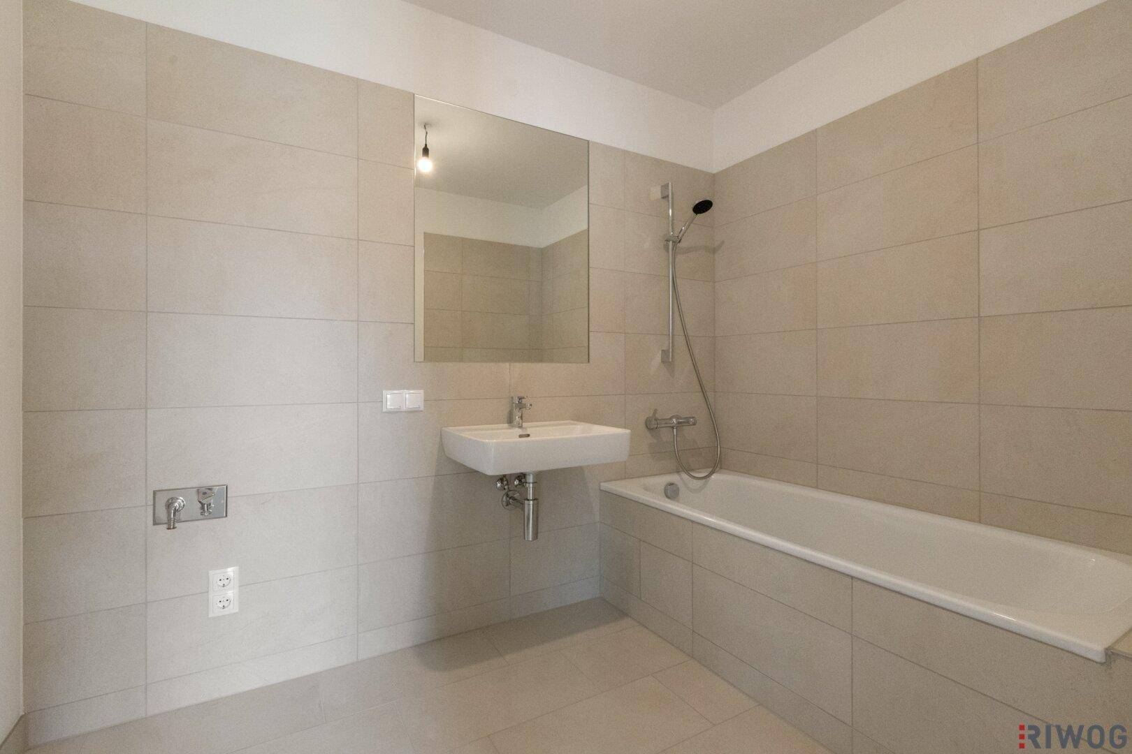 Modernes Badezimmer mit Badewanne, Wandfliesen und einem einzelnen Waschbecken.