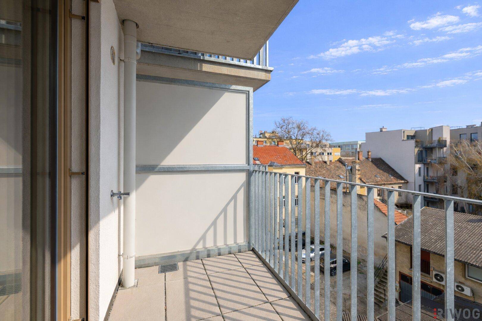 Heller Balkon mit Fliesenboden und Blick auf die umliegenden Gebäude, bereit zur individuellen Gestaltung.