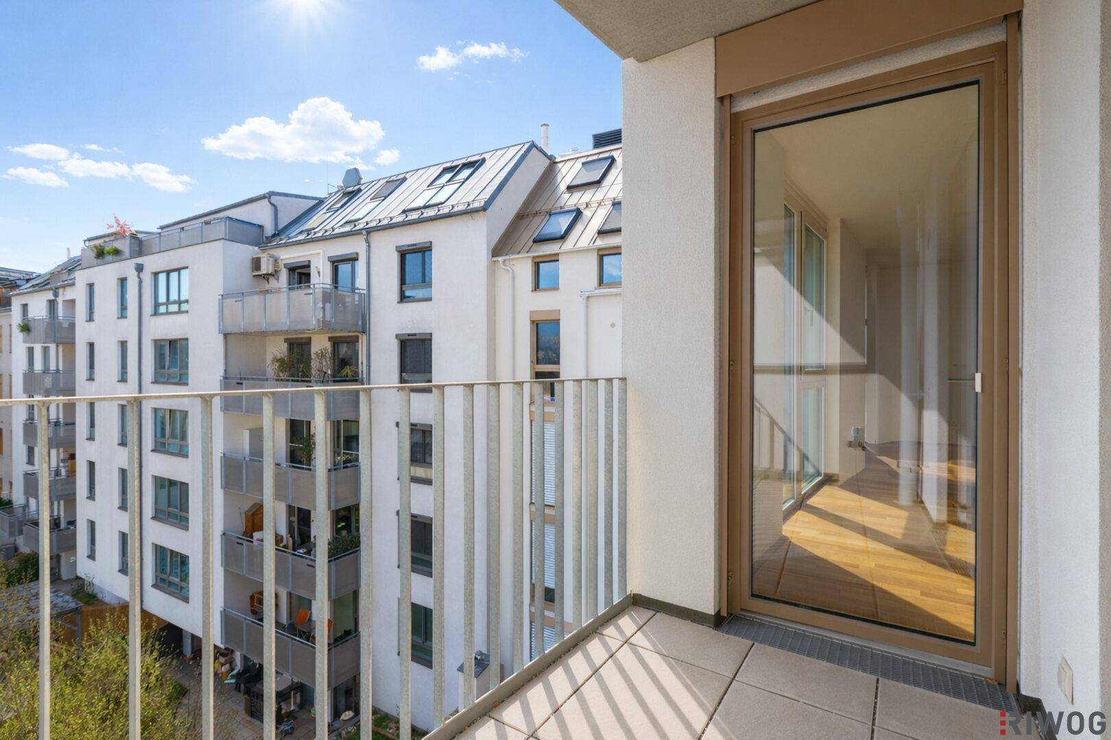 Heller Balkon mit Zugang zum Innenraum und weitem Blick über die städtische Umgebung.