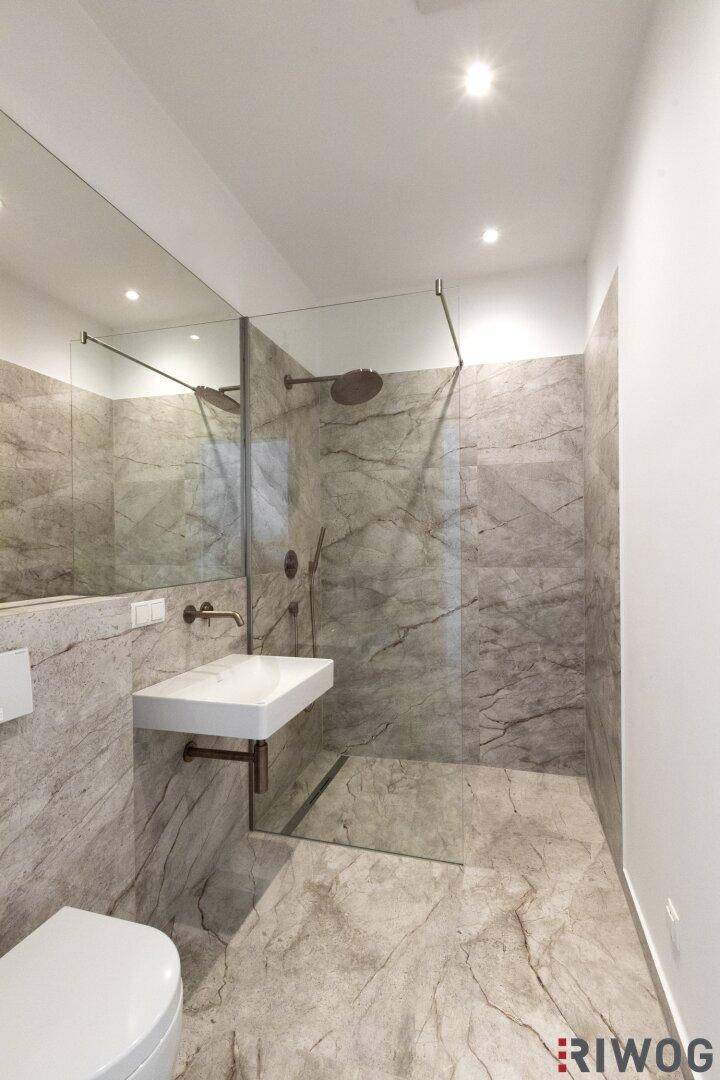 Modernes Badezimmer mit grauen Marmorfliesen, einer begehbaren Dusche und einem wandhängenden WC.