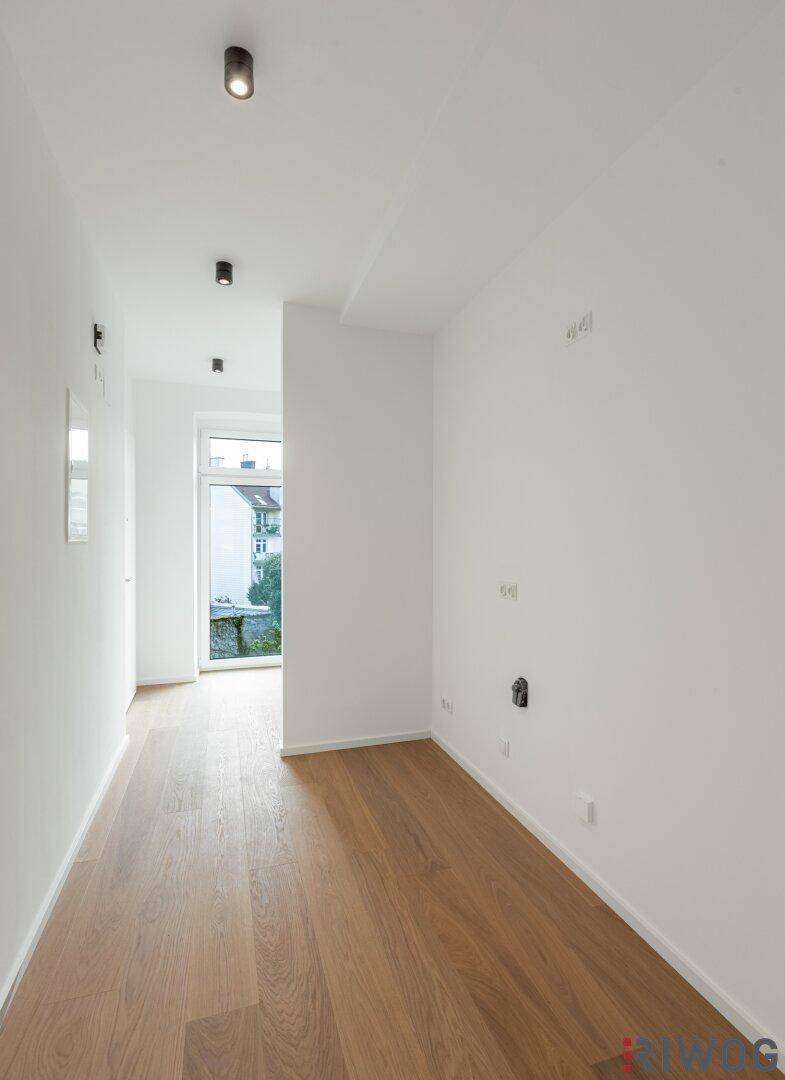 Heller Flur mit Holzboden und Zugang zu einem Außenbereich durch eine Glastür.