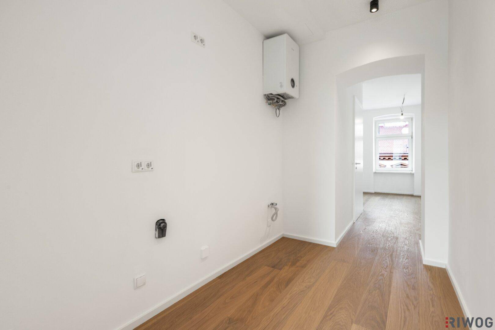 Funktionaler Raum mit Gastherme an der Wand und Anschlüssen für Haushaltsgeräte.
