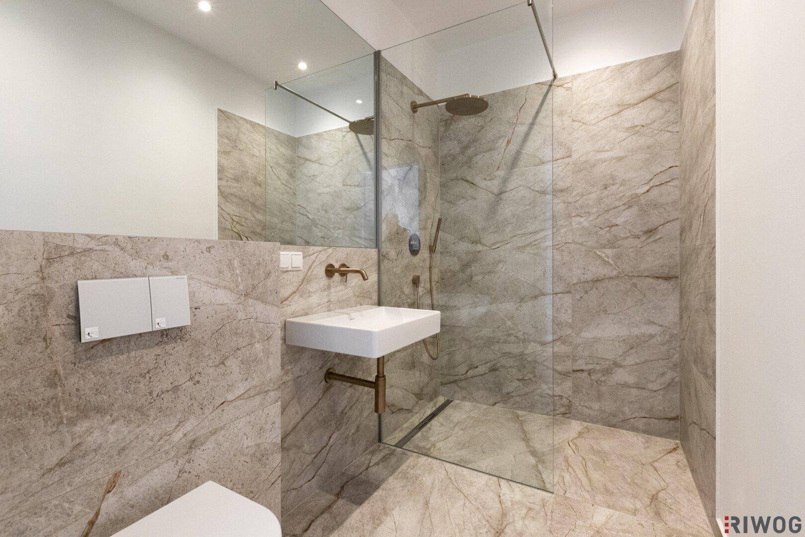 Modernes Badezimmer mit großformatigen Fliesen, bodengleicher Dusche und minimalistischem Waschbecken.