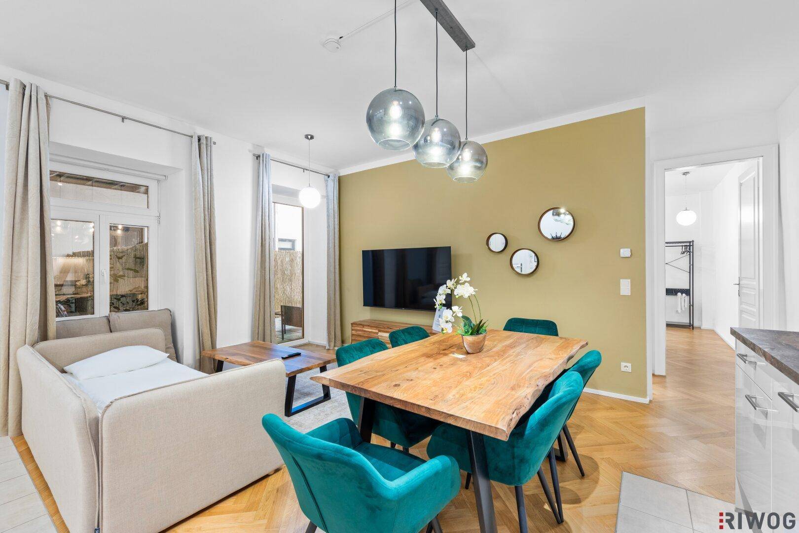 Gemütlicher Wohnbereich mit Essplatz, Fernseher und Zugang zu einem Balkon oder einer Terrasse.