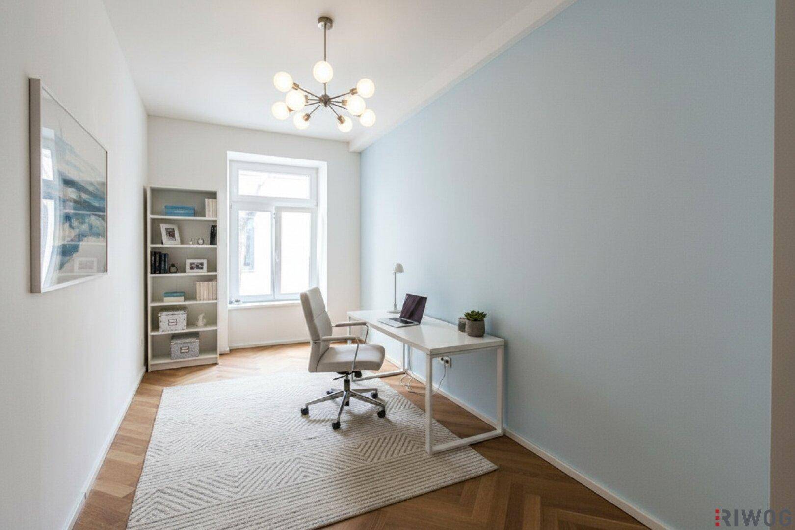 Ruhiges Arbeitszimmer mit Fischgrätparkett, Schreibtisch und einem großen Fenster für viel Tageslicht.