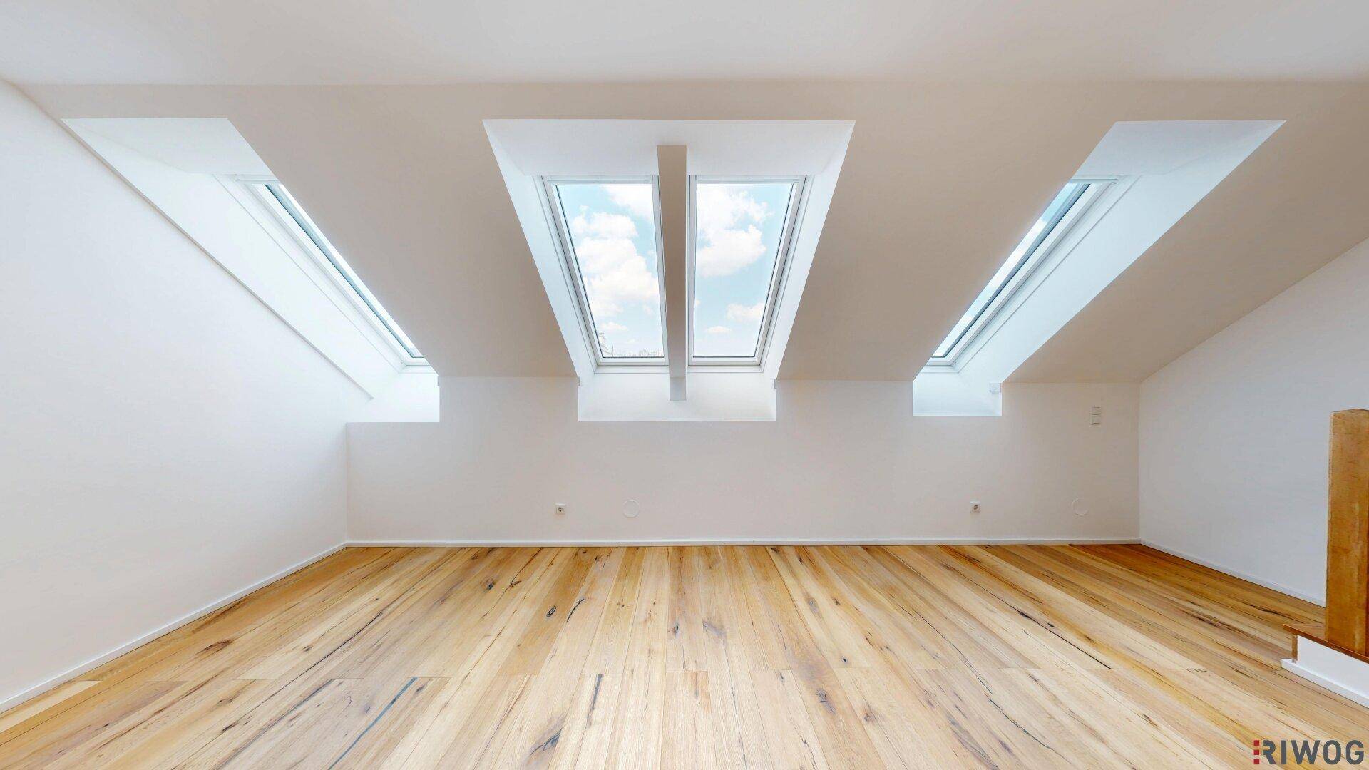 Leerer Raum mit Holzboden und mehreren Dachfenstern, ideal für individuelle Gestaltung.