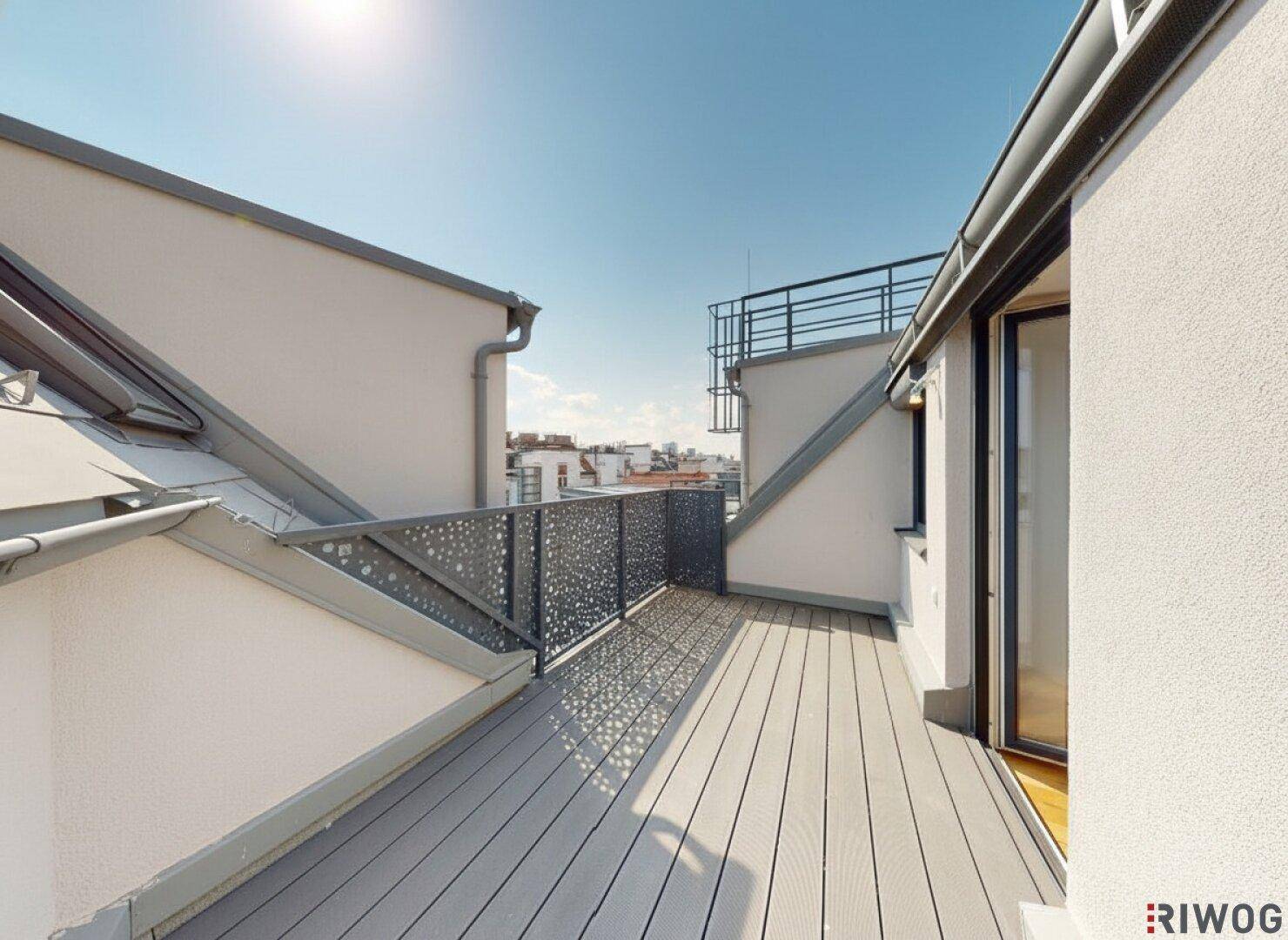Geräumige Dachterrasse mit Holzdielenboden und Blick auf die umliegenden Gebäude.