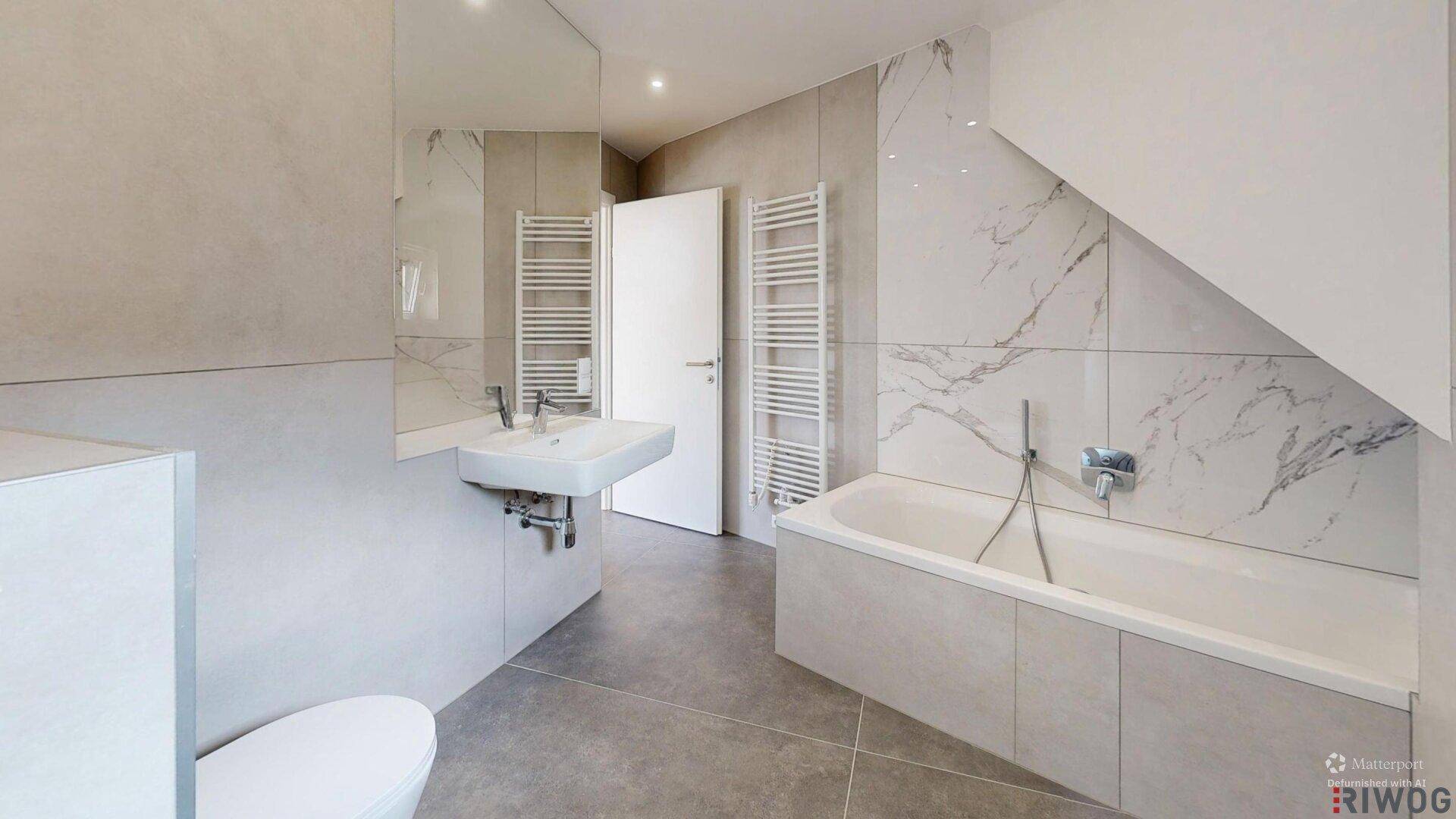 Modernes Badezimmer mit Badewanne, Waschbecken, beheiztem Handtuchhalter und Marmorfliesen.