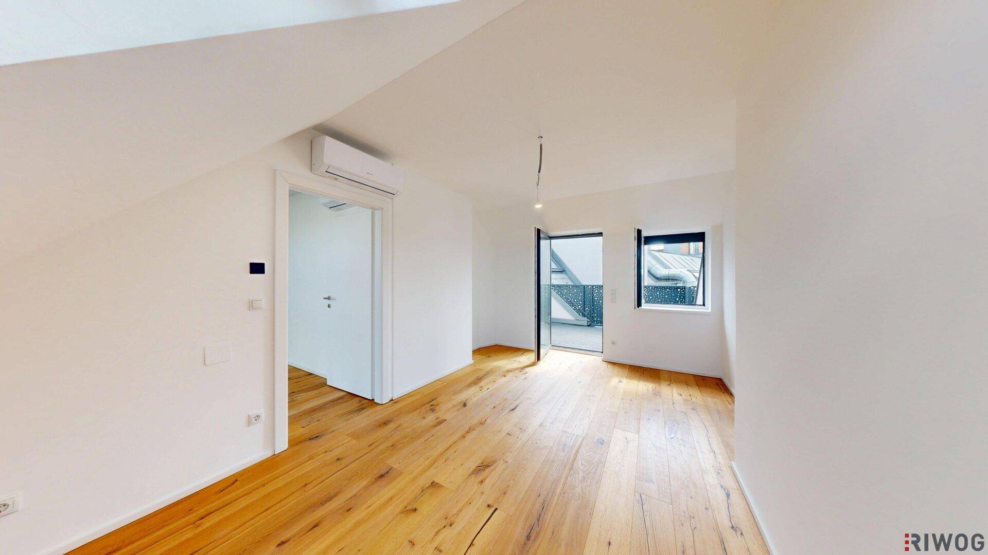 Heller leerer Raum mit Holzboden, Klimaanlage und Zugang zur Terrasse.