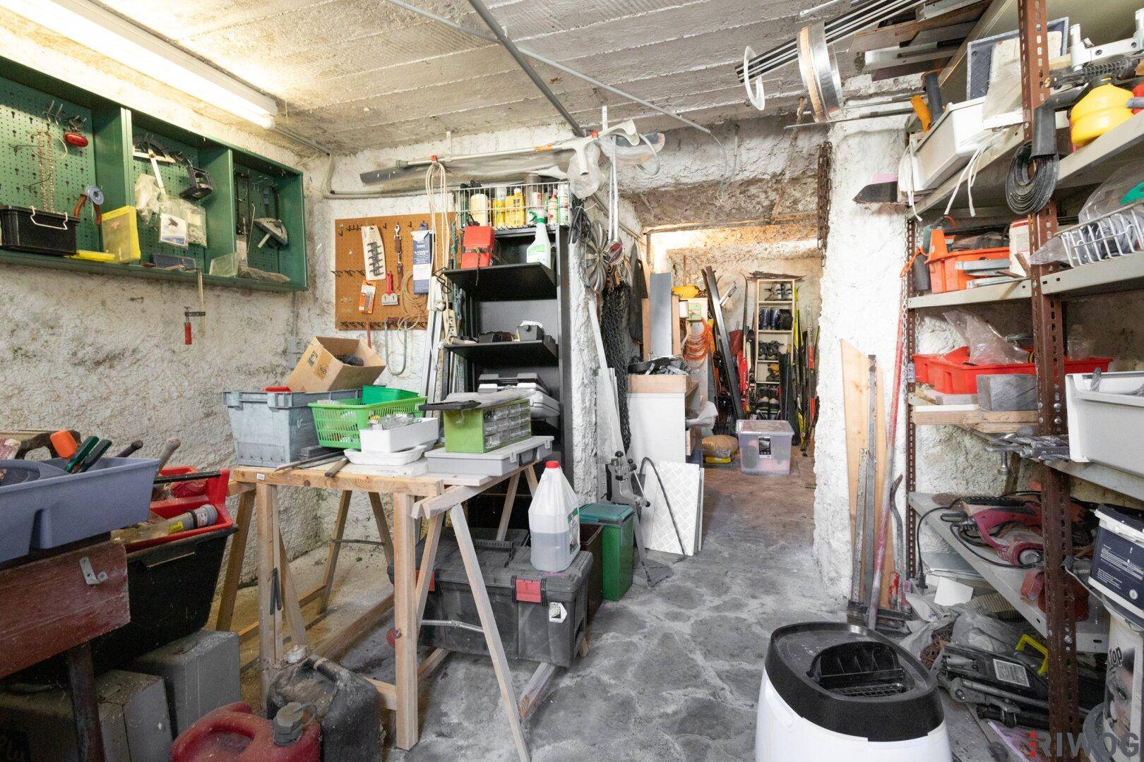 Unaufgeräumter Hauswirtschaftsraum im Keller mit Werkzeugen, Regalen und Arbeitsbereich.