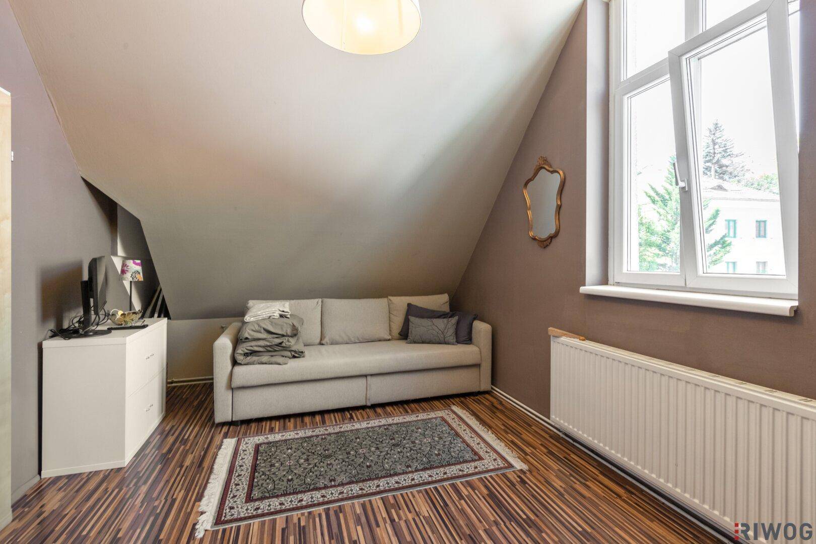 Gemütliches Schlafzimmer im Dachgeschoss mit Schrägdach, Sofa und Laminatboden.