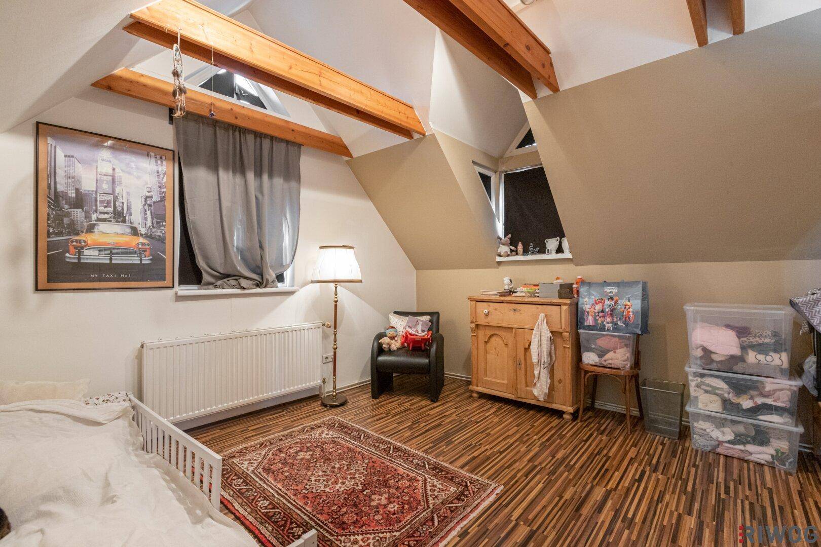Gemütliches Kinderzimmer im Dachgeschoss mit Holzbalken, Schrägdach und Laminatboden.