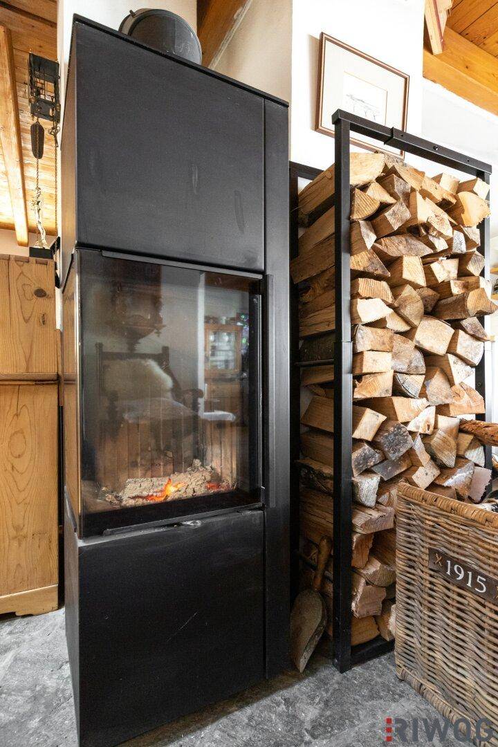 Moderner Kamin mit Sichtscheibe und gestapeltem Brennholz, bereit für gemütliche Abende.