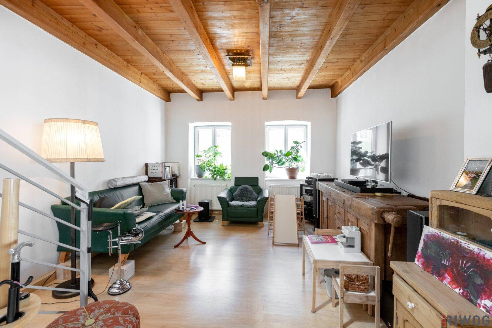 Wohnzimmer mit Holzbalkendecke, bequemen Sofas und einem Fernseher, ideal zum Entspannen.
