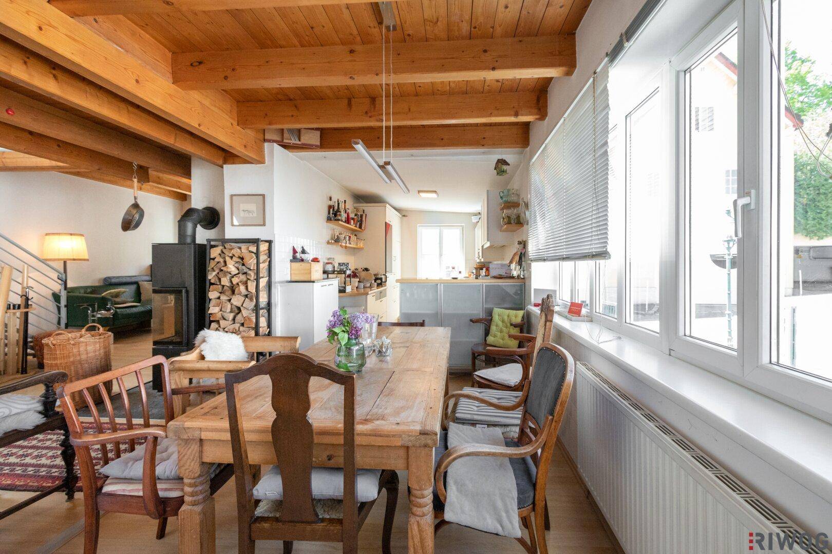 Heller Essbereich mit Holztisch und Blick auf die offene Küche im Hintergrund.