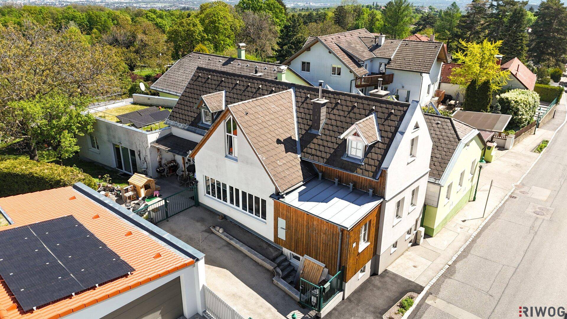 Luftaufnahme eines Wohnhauses mit Photovoltaikanlage und umliegenden Gärten.