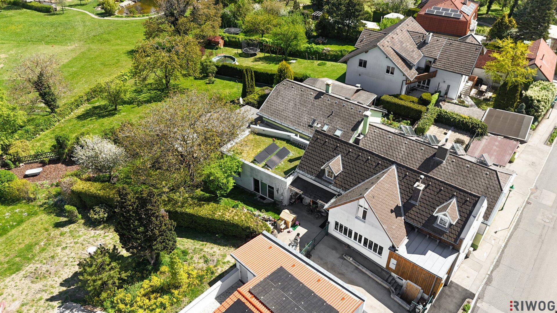 Luftaufnahme eines Wohnhauses mit Photovoltaikanlage, umgeben von Gärten und Natur.