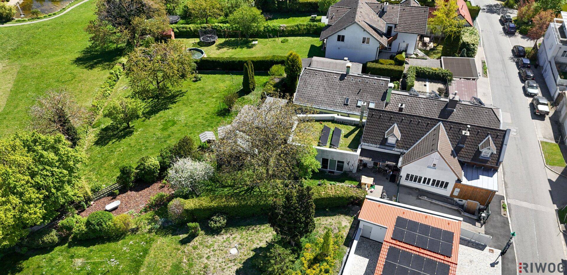 Luftaufnahme eines Wohnhauses mit Photovoltaikanlage, umgeben von Gärten und Bäumen.